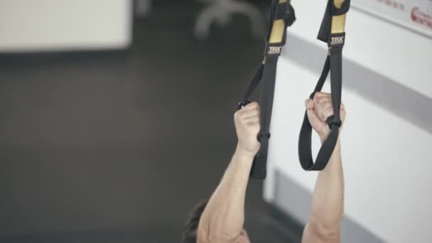 Atleta hombre usando bucles de fitness para pull ups ejercicio en el gimnasio . — Vídeos de Stock