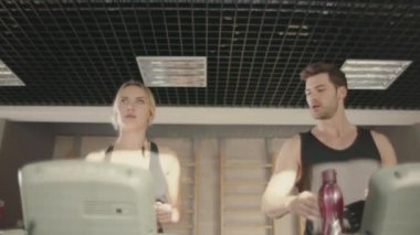 Yakışıklı adam fitness kulübünde koşu bandı makinesinde kadın ile flört.