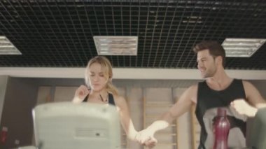 Neşeli fitness çift spor kulübünde koşu bandı makine üzerinde konuşurken.