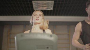 Spor salonunda konuşan konsantre spor çifti. Koşu bandında çalışan closeup çift