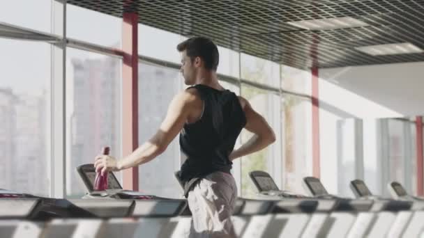 Koşu bandı makinesinde yoğun eğitim de şişeden kaçak adam içme suyu — Stok video