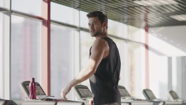 Un hombre guapo mirando en el gimnasio. Macho cinta de andar masculina en el gimnasio — Vídeo de stock