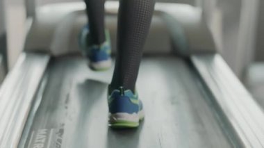Fitness salonunda koşu bandında çalışan yakın bacaklar. Fitness ayakkabılarının arka görünümü