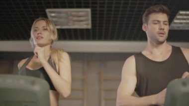 Fitness salonunda koşu bandı üzerinde genç adam içme suyu.