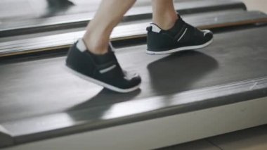 Fitness salonunda koşu bandında geri çalışan closeup ayaklar.