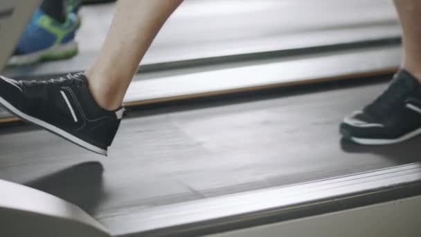Primer plano pies caminando en la cinta de correr en gimnasio de fitness lentamente . — Vídeos de Stock