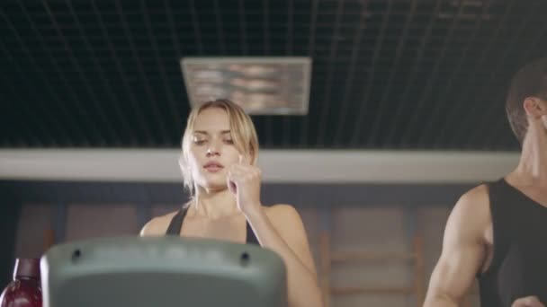 Concentrated couple running together on treadmill machine in gym club. — Stock Video