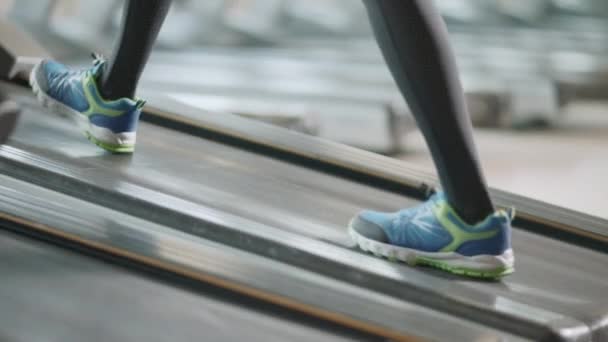 Zbliżenie dwie pary stóp poruszających się na bieżni w siłowni fitness. — Wideo stockowe