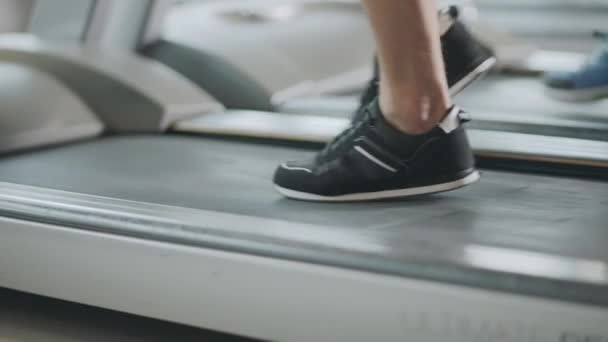 Zbliżenie stopy poruszające się na bieżni w siłowni fitness. — Wideo stockowe