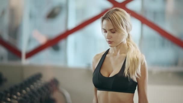 Mooie vrouwelijke trainer doet dumbbells oefeningen in fitness gym. — Stockvideo