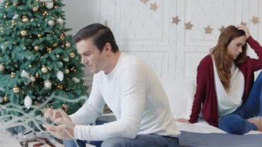 Dikkati dağılmış bir adam lüks evde cep telefonuyla mesaj atıyor. Gülümseyen koca karısını görmezden geliyor