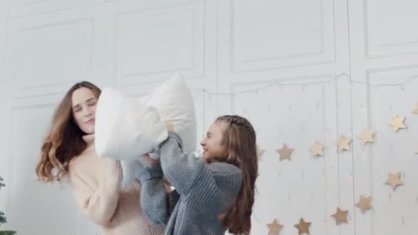 Closeup mãe e filha jogando travesseiros na cama no quarto de luxo . — Vídeo de Stock