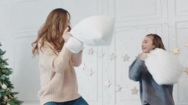 Closeup anne ve kızı birlikte uyku odasında yastık ile oynarken.