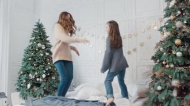 Neşeli anne ve kızı lüks evde yatakta dans partisi olan.
