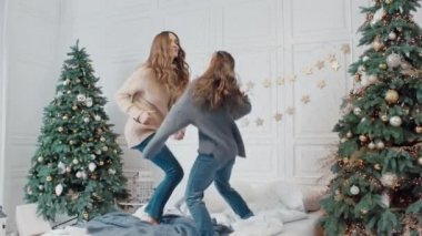 Mutlu anne ve kızı özel evde yatakta dans partisi yapma.