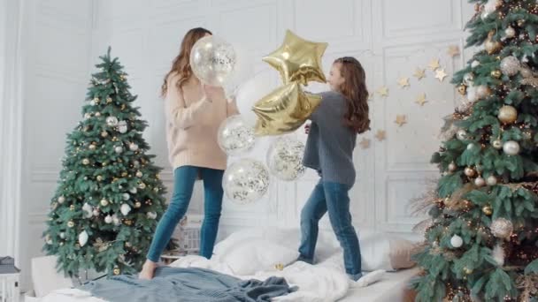 Gelukkige dames spelen met sterren ballonnen op bed in prive-huis. — Stockvideo
