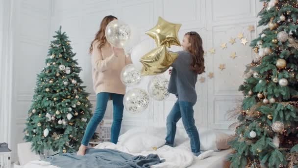 Happy ladies playing with star balloons on bed in private house. — Stock Video