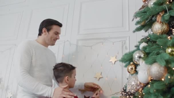 Glücklicher Vater und Sohn setzen gemeinsam goldenen Stern in Luxuszimmer an die Wand. — Stockvideo