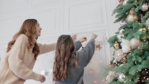 Sorrindo mãe e filha adolescente colocando guirlanda na parede na sala de estar . — Vídeo de Stock