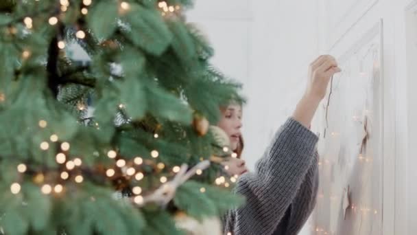 Leende kvinna kramas flicka nära julgran i vardagsrummet. — Stockvideo