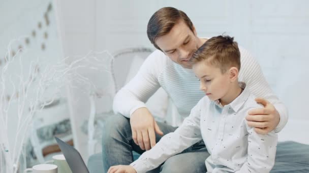 Appy ojciec przytulanie syn szuka ekranu komputera w nowoczesnym mieszkaniu. — Wideo stockowe