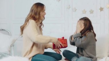 Gülümseyen kız lüks evde gözlerini kapatıyor. Güzel anne hediye sunan