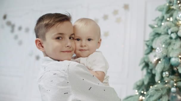 Retrato de hermanos felices cerca del árbol de Navidad en casa moderna . — Vídeos de Stock