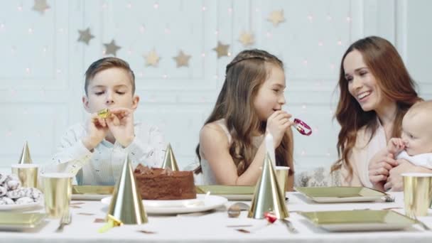 Familia feliz sentada en la mesa festiva con pipas de Navidad . — Vídeos de Stock