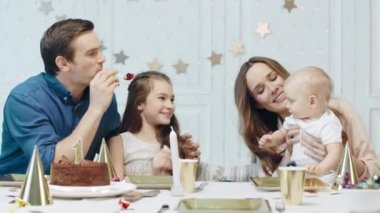 Oturma odasında şenlikli masada oturan iki çocuk ile Gülümseyen çift.