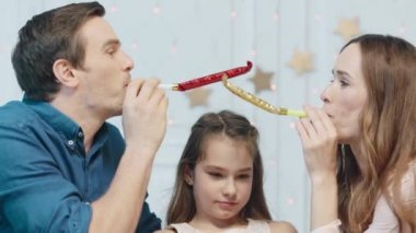 Mutlu aile oturma odasında birlikte noel borusu tootling.