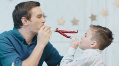 Gülen adam ve çocuk birlikte doğum günü boruları tootling.