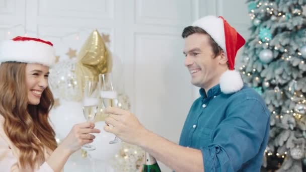 Glad par dricker champagne nära julgran — Stockvideo