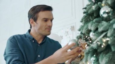 Closeup yakışıklı adam yeşil ağaç üzerinde gümüş top koyarak.