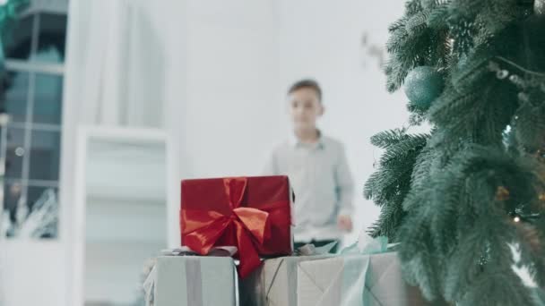 Closeup jovem cara tomando presente perto de árvore de natal em casa de luxo . — Vídeo de Stock