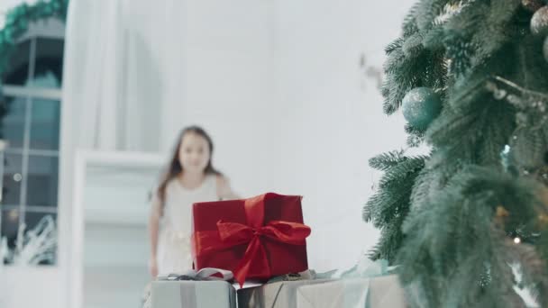 Happy girl prenant boîte cadeau près de l'arbre de Noël dans un appartement moderne . — Video