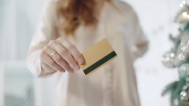 Primeros planos mujer mano mostrando tarjeta de crédito en chritmas habitación decorada . — Vídeos de Stock