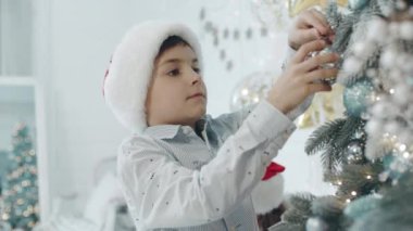 Oturma odasında noel ağacı dekorasyon ciddi çocuk.