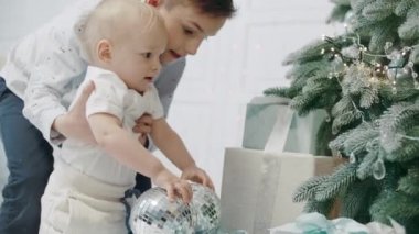 Oturma odasında noel ağacına dokunan iki kardeş.