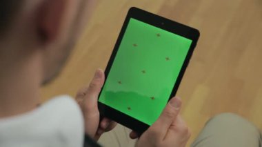 Yeşil ekranlı tableti elinde tutan genç adam. İşadamı tablet izliyor