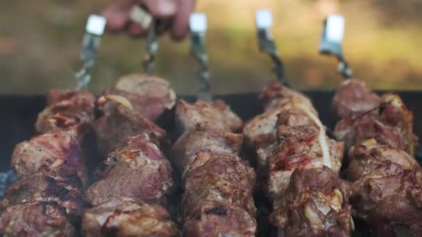 Ψητό κρέας μπάρμπεκιου σε ανοιχτή ψησταριά έξω. Κλείστε το αρσενικό χέρι που μετατρέπει το κρέας σουβλάκια — Αρχείο Βίντεο
