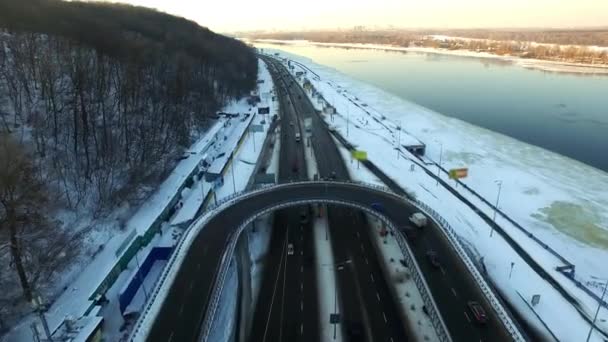 Автомобили на перекрестке дорог в зимнем городе. Вид с воздуха на автомобильное движение на зимнем шоссе — стоковое видео