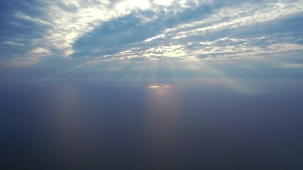 Sunrays penetrating clouds in sky above sea. Aerial view sunlight through clouds — Stock Video