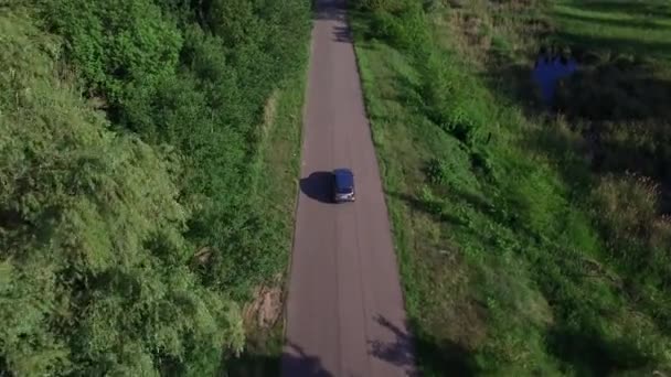 Drone ver carro dirigindo na estrada rural através da floresta verde — Vídeo de Stock