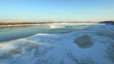 Aerial view frozen river in winter city. Birds flying over ice river