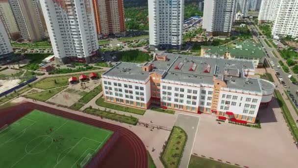 Estadio deportivo en el patio de la escuela en edificios de gran altura. Campo de fútbol vista aérea — Vídeo de stock