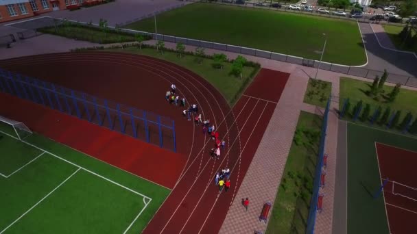 Schoolchild group walking on sport ground in school yard aerial view — Stockvideo