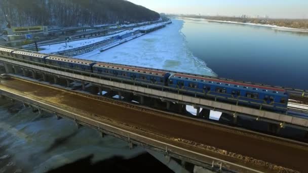 Vista aérea metro tren conducción en puente ferrocarril sobre invierno río paisaje — Vídeos de Stock