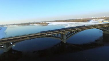 Drone görünümü etro tren kışın köprü demiryolu üzerinde sürme. Karayolu üzerinde araç trafiği