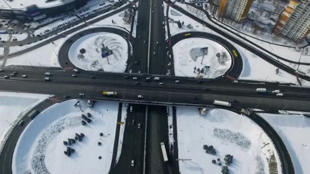 Шосе перетинається в зимовому місті. Повітряний вигляд автомобіля водіння по круговій дорозі — стокове відео