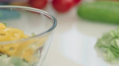 Şeffaf kasede taze sebze salatası. Salata hazırlayan eller